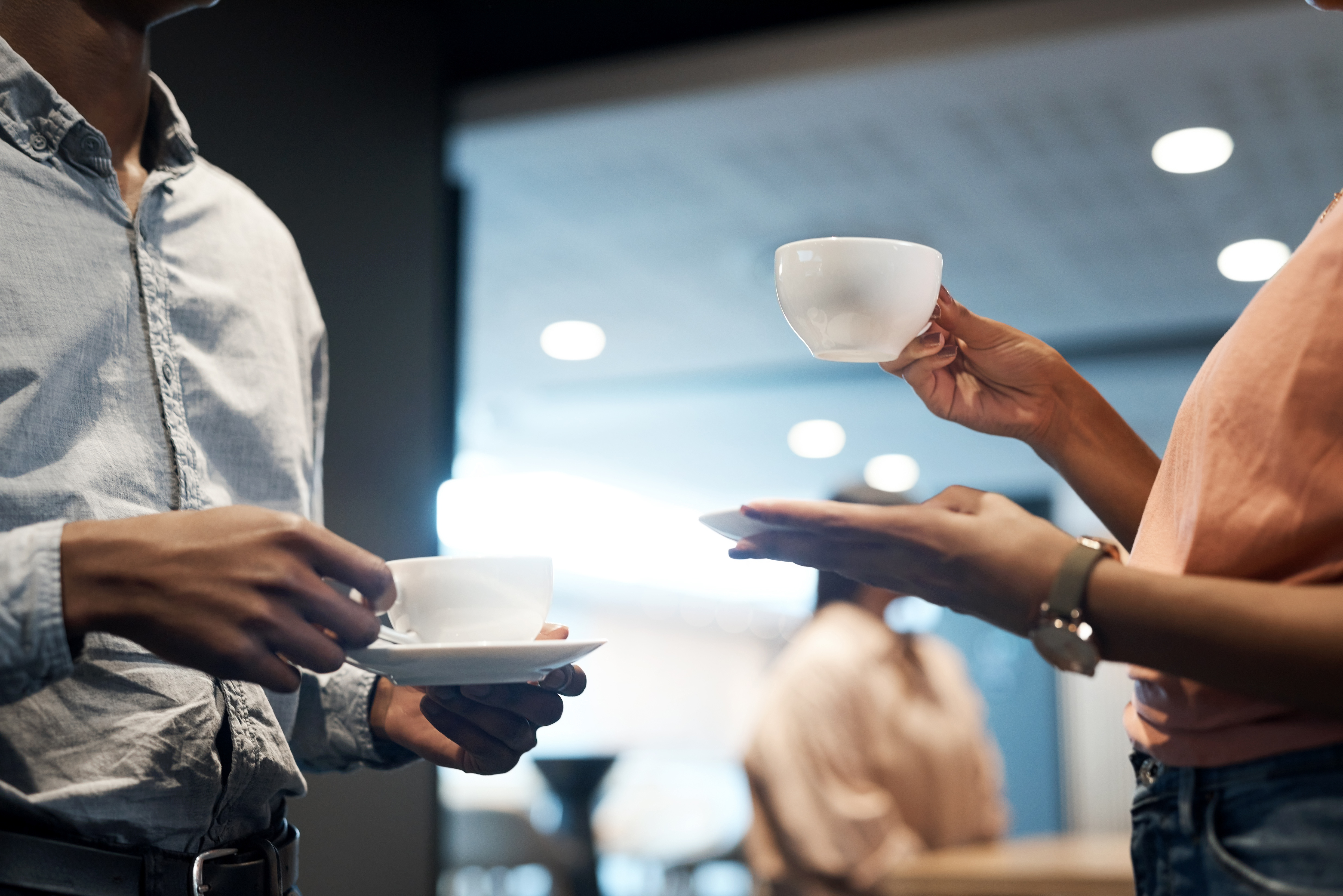 Two people having a conversation, holding cups of coffee